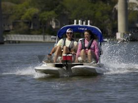 A couple enjoys a thrilling ride on a speedboat, splashing through the water — perfect for adventure seekers looking to explore the waterways.