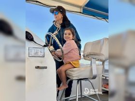 A joyful moment inside the boat's helm, featuring a child playfully steering while an adult supervises — perfect for family boating adventures.