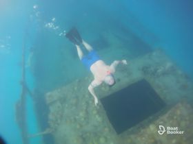 A snorkeler explores a sunken wreck underwater, showcasing the thrill of diving adventures and marine exploration.