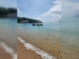 A sleek speedboat anchored in clear turquoise waters, showcasing a serene beachside view — perfect for a day of relaxation and adventure.