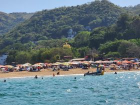 A vibrant beach scene filled with umbrellas and people enjoying the sun and water, showcasing a lively vacation atmosphere.