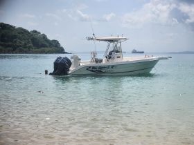 A person enjoys a refreshing swim near a boat anchored in clear waters, perfect for beach outings and water activities.
