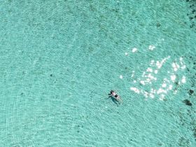 A child floats peacefully in crystal-clear waters, showcasing the serene beauty of a tropical paradise — perfect for family adventures and relaxation.