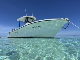 A stunning view of the 'Bati Ni Wai' speedboat anchored in crystal-clear waters, showcasing its sleek design against a vibrant blue sky.