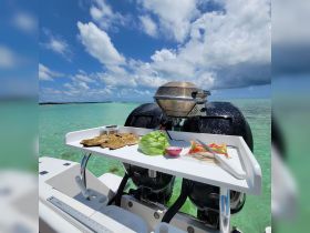 A well-equipped boat features a grill with fresh ingredients laid out, perfect for outdoor cooking adventures on the water.