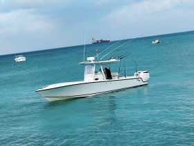 A sleek speedboat navigates through clear turquoise waters, showcasing its fishing gear and perfect for a day on the ocean.