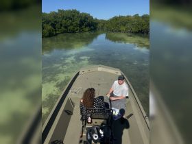A couple enjoys a relaxing moment on a boat surrounded by mangroves, sipping drinks and soaking in the serene atmosphere.