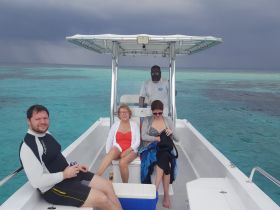 A group of friends relaxes on a boat in the turquoise waters, enjoying their time on the ocean. Perfect for a day of adventure or leisure on the water.
