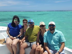 A cheerful group of friends enjoys a sunny day on a boat, surrounded by stunning turquoise waters — perfect for memorable outings and adventures.