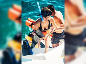 A group enjoys a snorkeling adventure, climbing aboard after exploring vibrant underwater life — a perfect day on the water.