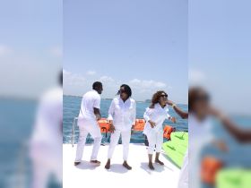 A lively group enjoys a fun moment on a boat, dressed in white, celebrating together under the sun — perfect for memorable outings on the water.