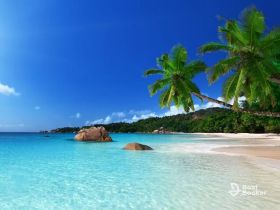 A stunning tropical beach scene featuring crystal-clear waters, lush greenery, and rocky formations, perfect for showcasing idyllic island getaways.