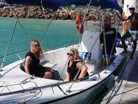 Two friends enjoy their time aboard a boat with crew members, capturing the essence of a fun day on the water.