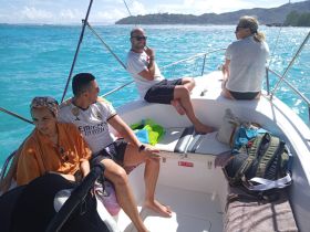 A cheerful group enjoys a sunny day on a boat, surrounded by stunning turquoise waters — perfect for a memorable outing with friends.