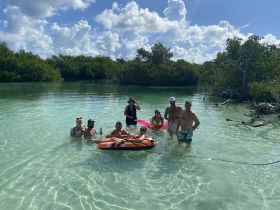 A joyful group enjoys a fun day in the shallow waters surrounded by mangroves, perfect for family outings and water activities.
