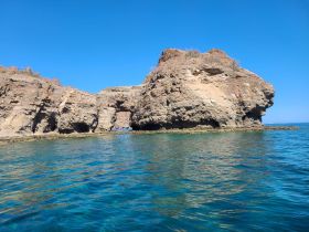 A stunning view of a rocky coastline with clear blue waters, perfect for exploring natural landmarks and enjoying the beauty of the ocean.