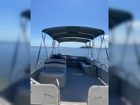 Interior view of a spacious pontoon boat featuring comfortable seating and a shaded lounge area, perfect for relaxing on the water.