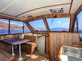 Interior view of a stylish boat cabin featuring comfortable seating and a helm, perfect for enjoying scenic views while cruising.