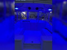 Interior view of a boat cabin illuminated with blue lights, showcasing the seating and layout — perfect for evening cruises or relaxing onboard.