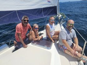 A cheerful group of friends enjoys a sunny day sailing on the water, capturing the essence of friendship and adventure at sea.
