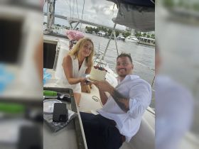 A couple celebrates with a cake aboard a yacht, capturing a special moment on the water — perfect for anniversaries or romantic outings.