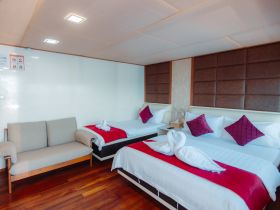 A cozy cabin interior featuring two beds and a comfortable seating area, perfect for relaxing during a boat trip.