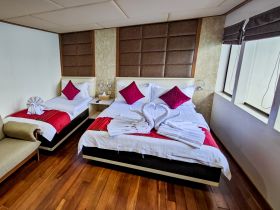 A cozy cabin interior featuring two neatly arranged beds with decorative pillows and towel art, perfect for relaxing on a boat.