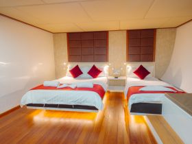 A cozy and modern boat cabin featuring two neatly arranged beds with elegant decor, perfect for comfortable overnight stays on the water.