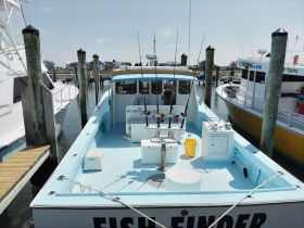 Interior view of a fishing boat, showcasing the helm and fishing gear, perfect for anglers looking for a day on the water.
