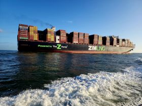 A striking view of a ZIM cargo ship navigating through the waters, showcasing its impressive container load and sleek design.