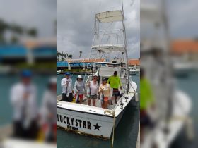 A group of anglers proudly display their catch aboard the Lucky Star in Aruba, celebrating a successful fishing trip.