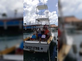 A cheerful group poses aboard the 'Lucky Star' in Aruba, ready for a fishing adventure. This family-friendly experience showcases the joy of boating in beautiful waters.