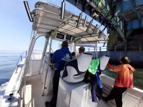 Inside view of a boat's helm with passengers seated, showcasing the operational area and seating arrangements. Ideal for fishing or leisure trips.