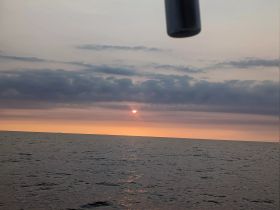 A serene sunset view over the ocean, captured from a boat, showcasing the tranquil beauty of the water and sky.