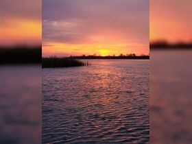 A stunning sunset casts vibrant colors over the water, creating a picturesque scene perfect for romantic evenings or serene boat trips.