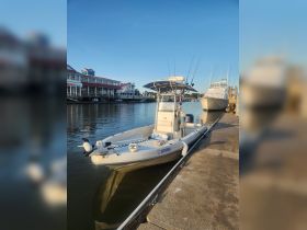 A sleek center console boat docked at the marina, showcasing its design against a clear blue sky — perfect for fishing or leisure outings.