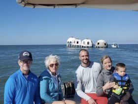 A family enjoys a day on the water, posing in front of unique structures while taking in the beautiful scenery — perfect for memorable boating adventures.