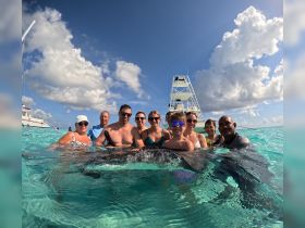 A joyful group interacts with a stingray in crystal-clear waters, creating unforgettable memories during their aquatic adventure.