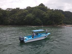 Two fishermen enjoy a day out on the water, casting their lines from a vibrant boat surrounded by lush greenery — a perfect setting for a fishing adventure.