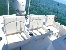 Interior view of a boat's seating area featuring comfortable white seats and a fishing rod holder, perfect for a day on the water.