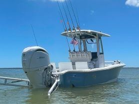 A sleek center console boat anchored in calm waters, showcasing its fishing gear and American flag — perfect for a day on the water.