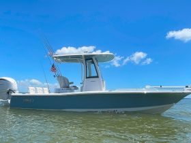 A sleek speedboat captured from the side, showcasing its design against a clear blue sky and calm waters — perfect for fishing or leisure outings.
