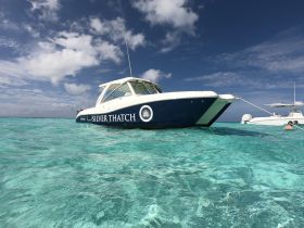 A sleek speedboat named 'Silver Thatch' glides through crystal-clear waters, showcasing the perfect day for boating adventures.
