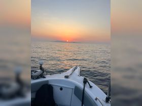 A serene view from the bow of a boat at sunset, showcasing the tranquil waters and distant islands — perfect for peaceful evening cruises.