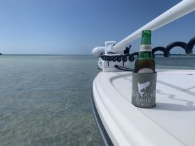A refreshing lager sits in a cozy on the deck of a boat, perfect for enjoying the serene waters of Key West — an ideal setting for relaxation and leisure.