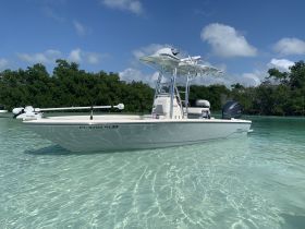A sleek center console boat anchored in crystal-clear waters, surrounded by lush greenery — perfect for fishing or leisurely outings.