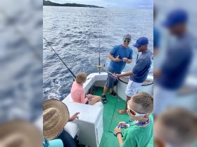 A group of children and adults enjoy a fishing trip on the ocean, showcasing the excitement of family bonding and adventure on the water.