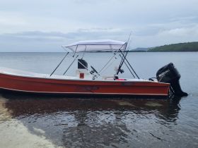 A vibrant speedboat is docked at the water's edge, showcasing its sleek design and fishing gear, perfect for a day of adventure on the water.