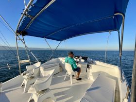 A view of the helm area inside a boat, featuring a captain at the wheel and comfortable seating, ideal for navigating the open waters.