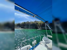 A picturesque view from a boat showcasing the vibrant green waters and a paddleboarder in the distance, perfect for capturing the essence of a relaxing day on the water.